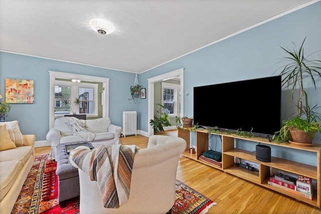 living room featuring radiator heating unit, baseboards, crown molding, and wood finished floors