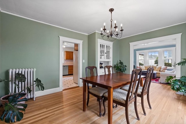 dining room with an inviting chandelier, crown molding, radiator, and light wood finished floors
