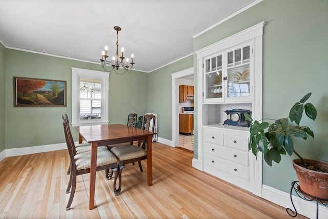 dining area featuring light wood-type flooring, ornamental molding, baseboards, and a chandelier