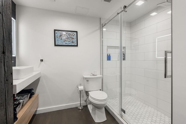 bathroom with hardwood / wood-style flooring, a shower with door, and toilet