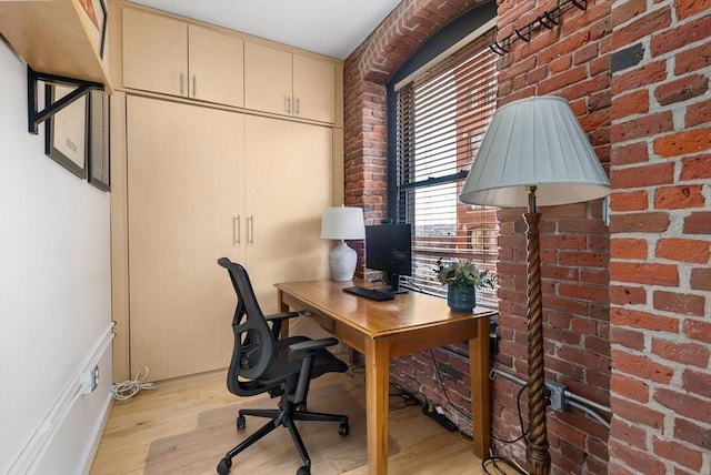 office area featuring brick wall and light hardwood / wood-style flooring