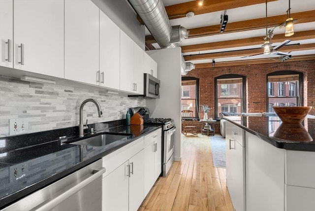 kitchen with stainless steel appliances, sink, white cabinets, and beam ceiling