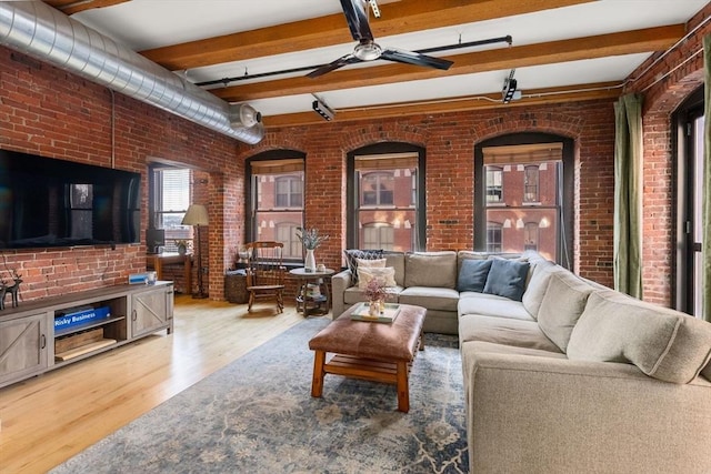 living room with hardwood / wood-style floors, beamed ceiling, and brick wall