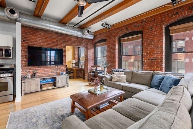 living room featuring brick wall, beam ceiling, and light wood-type flooring