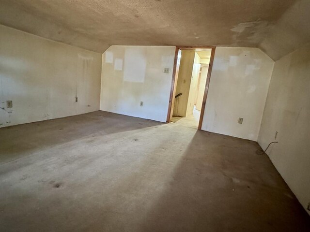 bonus room featuring vaulted ceiling and concrete flooring