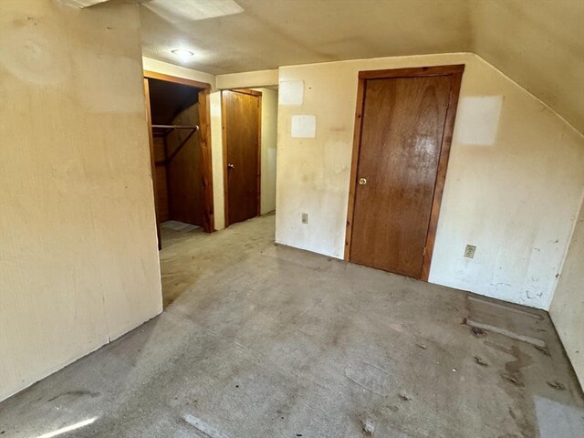 interior space featuring concrete floors and vaulted ceiling