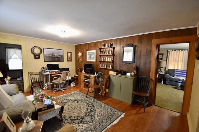 living room with ornamental molding, wood-type flooring, and wooden walls