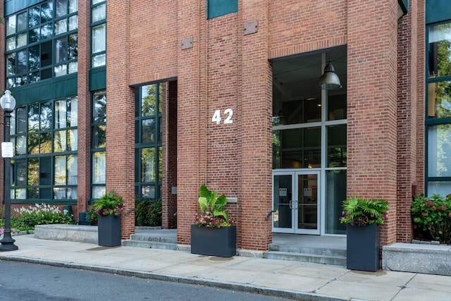 view of exterior entry featuring french doors and brick siding