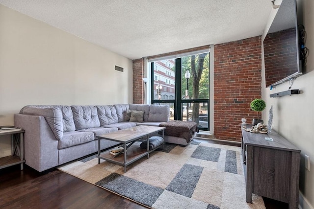 living area with a textured ceiling, visible vents, a wall of windows, and wood finished floors