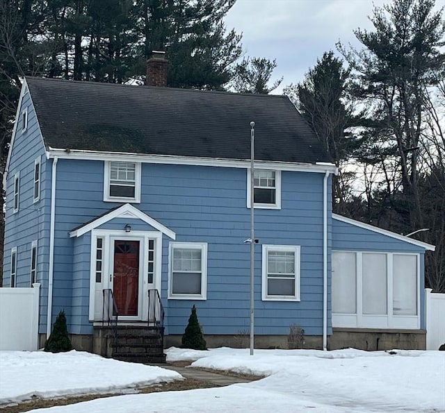 view of front of home with a sunroom, fence, and a chimney