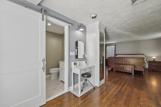 bedroom featuring ensuite bathroom, baseboards, and wood finished floors