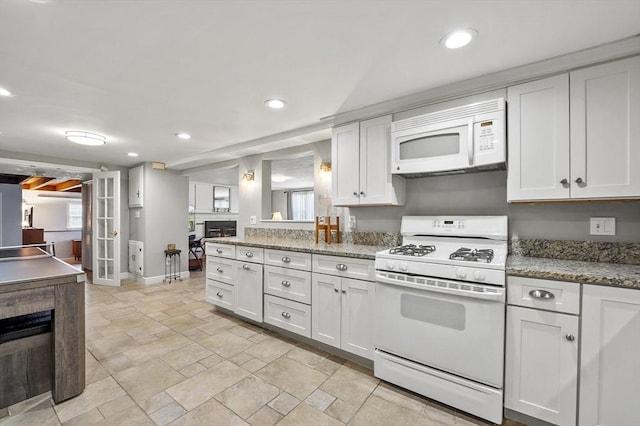 kitchen featuring stone finish floor, white cabinetry, baseboards, recessed lighting, and white appliances