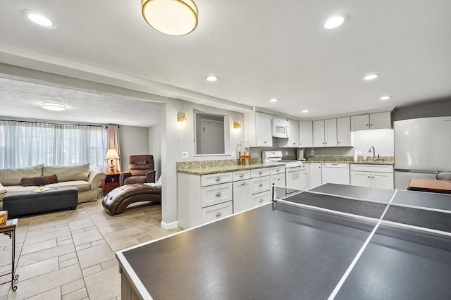 kitchen with a sink, white cabinets, white appliances, and open floor plan