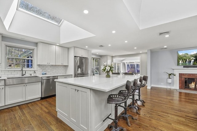 kitchen with visible vents, a sink, appliances with stainless steel finishes, and dark wood-style floors
