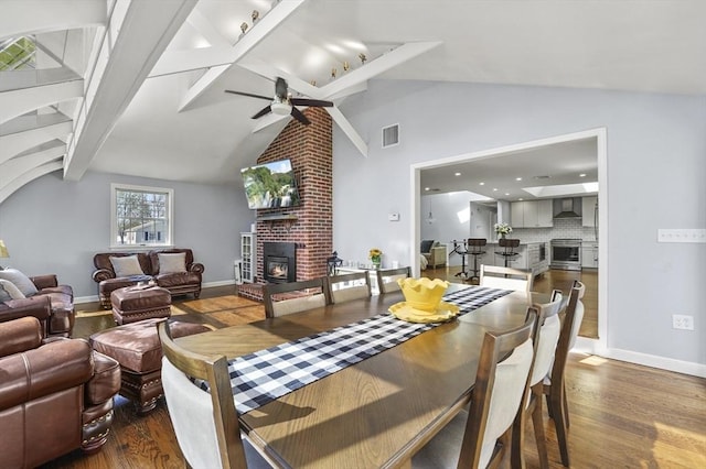 dining space with ceiling fan, visible vents, dark wood-type flooring, and a fireplace