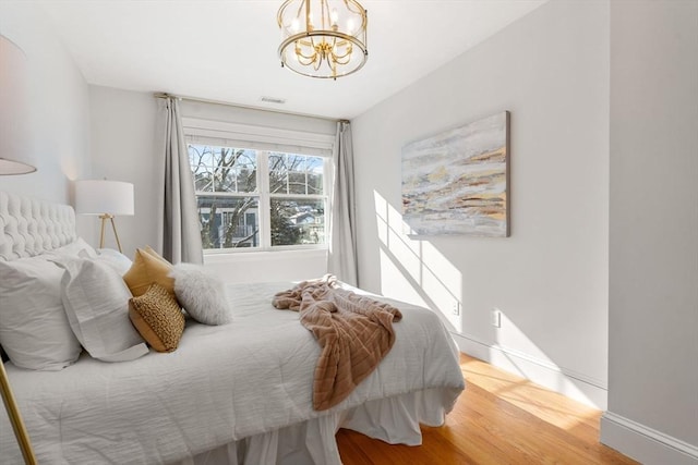 bedroom featuring wood-type flooring and a chandelier