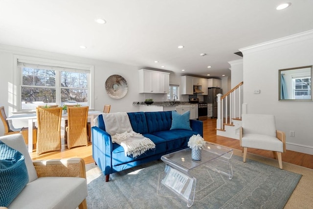 living room with sink, crown molding, and light wood-type flooring