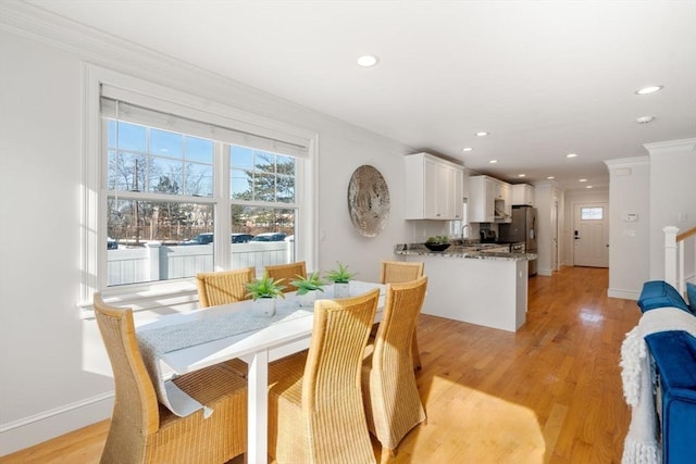 dining room featuring sink, light hardwood / wood-style flooring, and ornamental molding