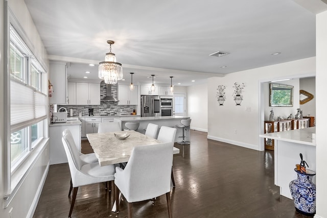 dining area featuring dark wood-type flooring, a notable chandelier, and plenty of natural light