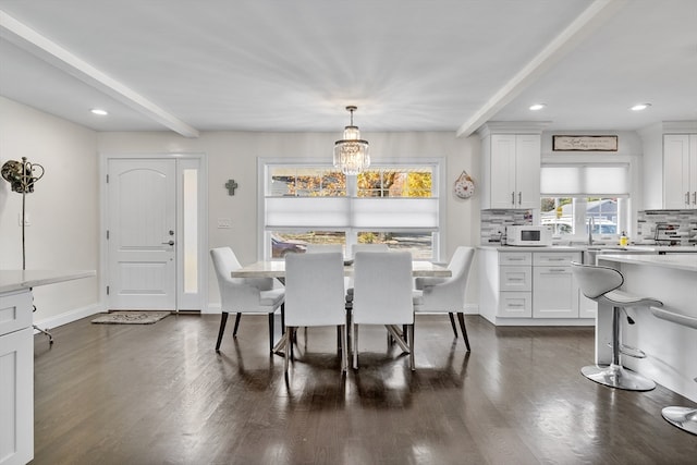 dining area featuring a notable chandelier, beam ceiling, and dark wood-type flooring