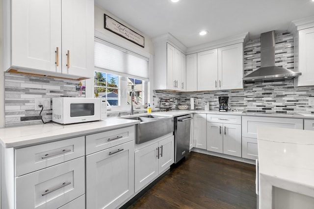 kitchen with wall chimney exhaust hood, stainless steel dishwasher, sink, and white cabinetry