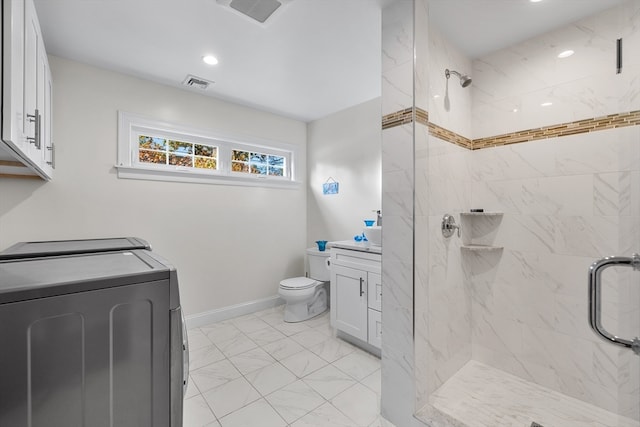 bathroom featuring vanity, a tile shower, independent washer and dryer, and toilet