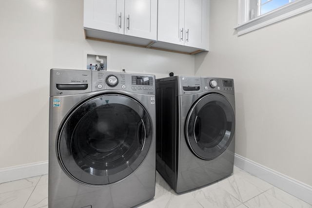 clothes washing area featuring cabinets and washer and clothes dryer