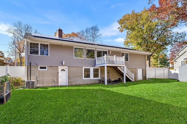 back of property with a wooden deck, cooling unit, and a yard