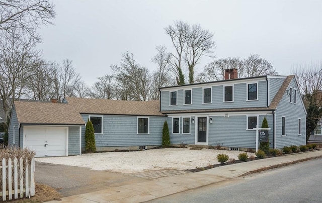 view of front of house featuring a chimney, driveway, a shingled roof, and a garage