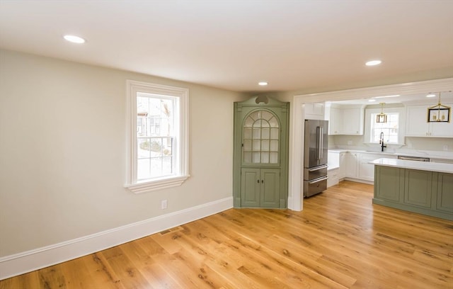 kitchen featuring high end refrigerator, white cabinetry, light countertops, and light wood-type flooring