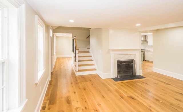 unfurnished living room with stairway, light wood-style flooring, baseboards, and visible vents
