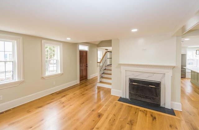 unfurnished living room featuring visible vents, light wood-style flooring, stairs, and baseboards