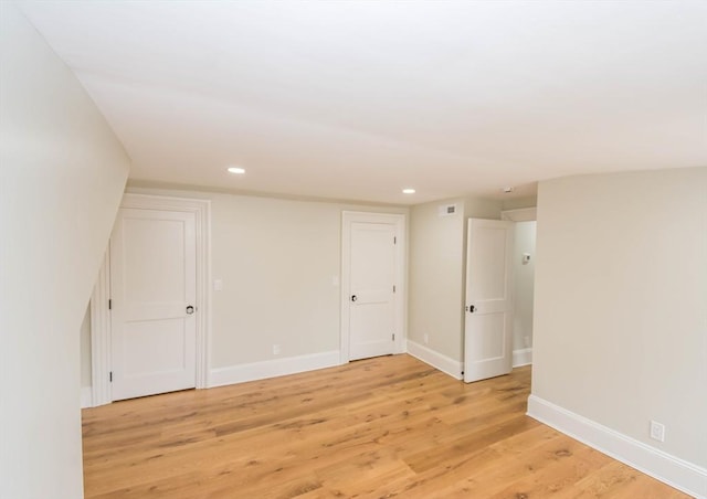 empty room featuring light wood finished floors, recessed lighting, and baseboards