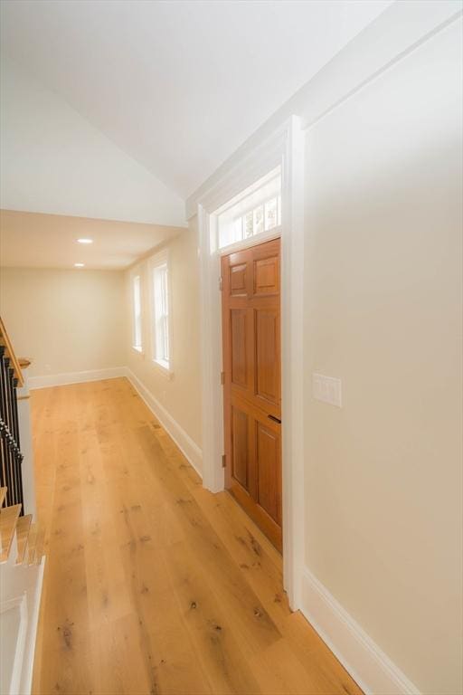 entrance foyer featuring baseboards, lofted ceiling, light wood-style floors, and stairs
