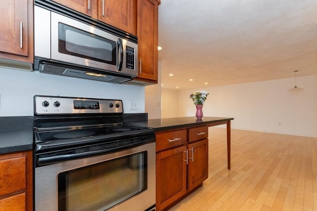 115 Highland Ave Unit 11, Somerville, MA 02143 - kitchen with stainless steel appliances, brown cabinets, dark countertops, light wood-style floors, and recessed lighting
