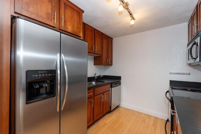 115 Highland Ave Unit 11, Somerville, MA 02143 - kitchen featuring appliances with stainless steel finishes, a sink, dark countertops, baseboards, and light wood-style flooring