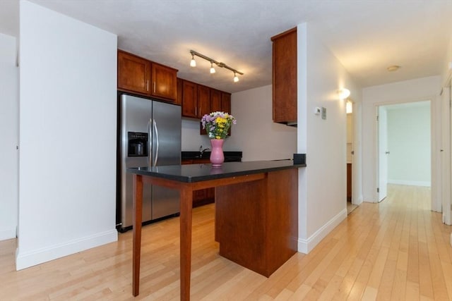 115 Highland Ave Unit 11, Somerville, MA 02143 - kitchen with stainless steel fridge, dark countertops, light wood-style floors, baseboards, and a peninsula