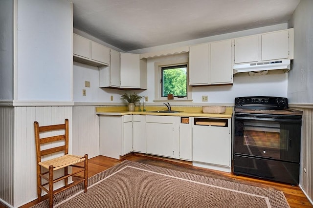 154 N Maple St, Northampton, MA 01062 - kitchen featuring black range with electric stovetop, under cabinet range hood, light countertops, wood finished floors, and a wainscoted wall