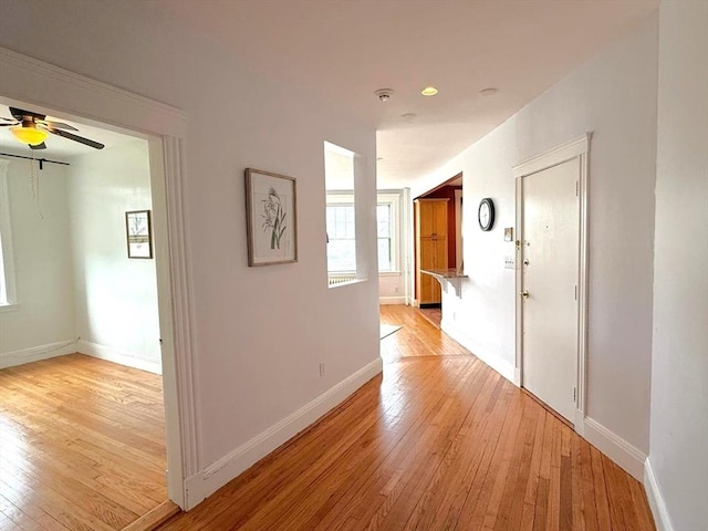 hall featuring light wood-type flooring and baseboards