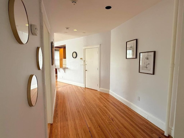 hall with light wood-style flooring and baseboards