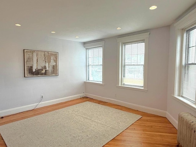 spare room with radiator heating unit, light wood finished floors, plenty of natural light, and recessed lighting