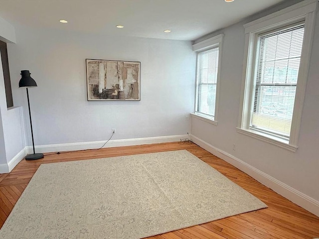 empty room with wood finished floors, baseboards, and recessed lighting