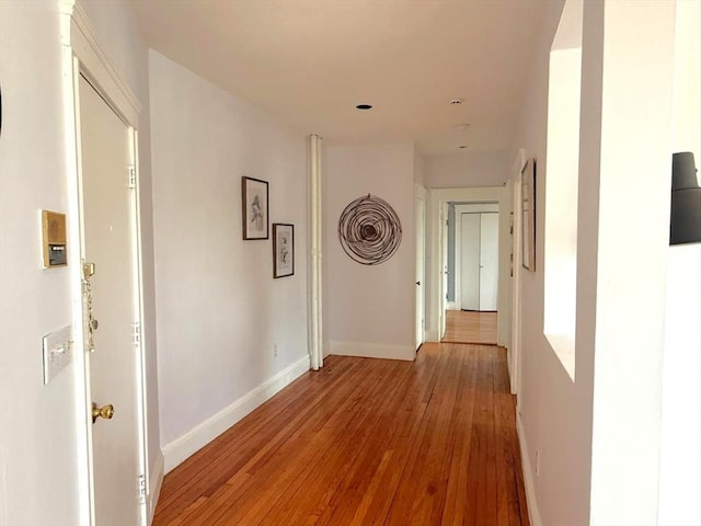 hallway with light wood-type flooring and baseboards
