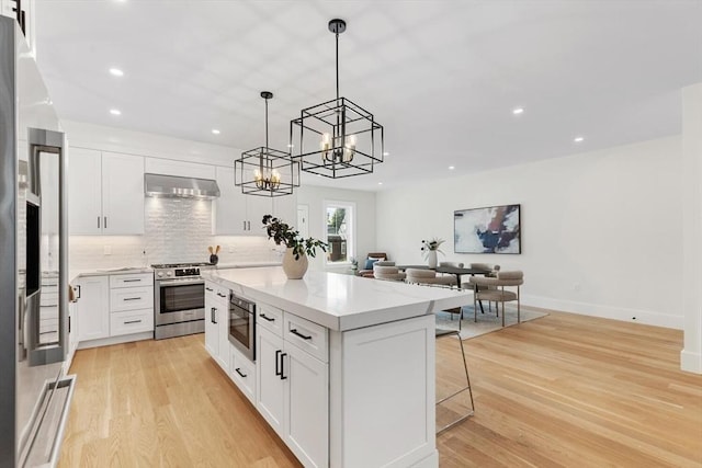 kitchen with white cabinets, exhaust hood, and appliances with stainless steel finishes