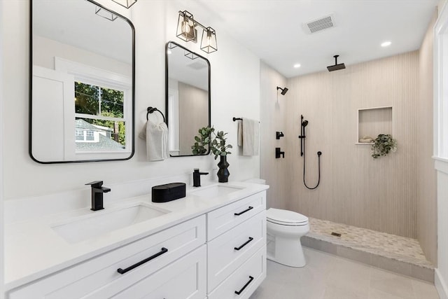 bathroom featuring a shower, tile patterned flooring, vanity, and toilet