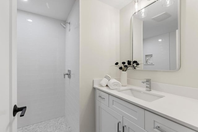 bathroom featuring a tile shower and vanity