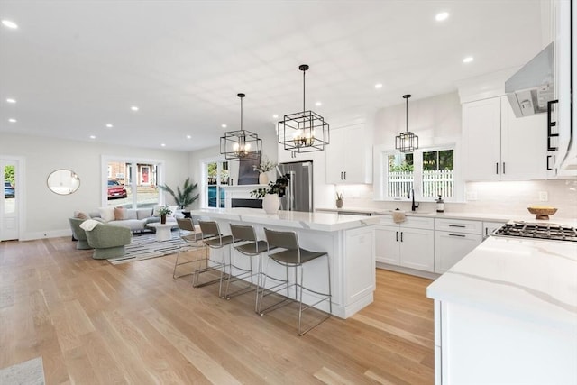 kitchen featuring a center island, stainless steel fridge, pendant lighting, light hardwood / wood-style floors, and white cabinets