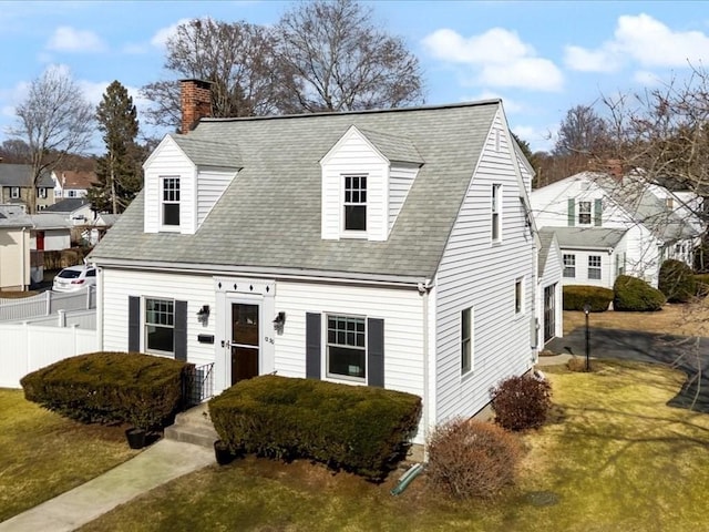 cape cod house featuring a shingled roof, a chimney, a front yard, and fence