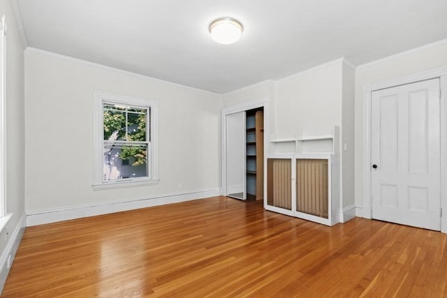 781 Highland Ave, Needham, MA 02494 - unfurnished bedroom with wood finished floors, crown molding, two closets, and baseboards