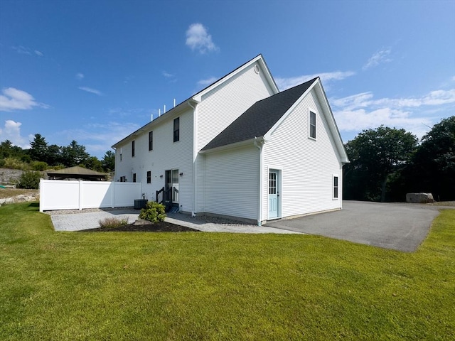 rear view of house with a lawn, central air condition unit, and a patio